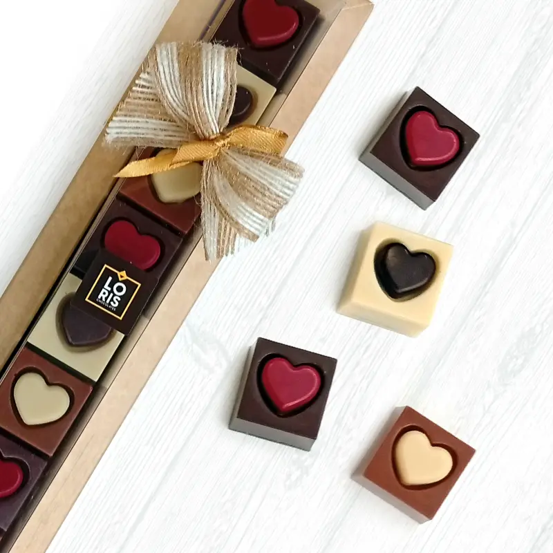 Caja de 8 bombones corazón de chocolate negro, chocolate con leche de almendra y chocolate blanco, con praliné de almendra y frambuesa, praliné rústico de avellana y praliné de pistacho, elaborados con ingredientes 100 % de origen vegetal, sin lácteos ni gluten
