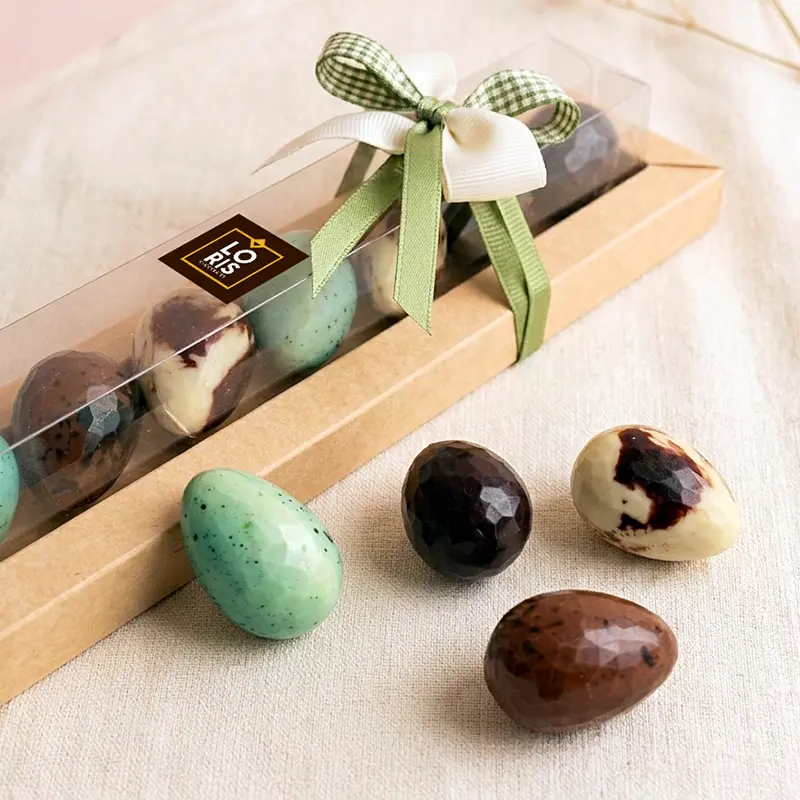 Caja Pascua con 8 huevos de chocolate rellenos de praliné rústico de avellana, almendra y coco tostado, pistacho, almendra y naranja confitada, elaborados con ingredientes 100 % de origen vegetal, sin lácteos y sin gluten.